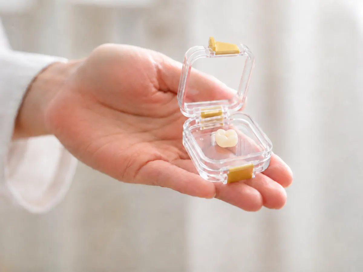 A hand holding an Ivorymade dental crown case.